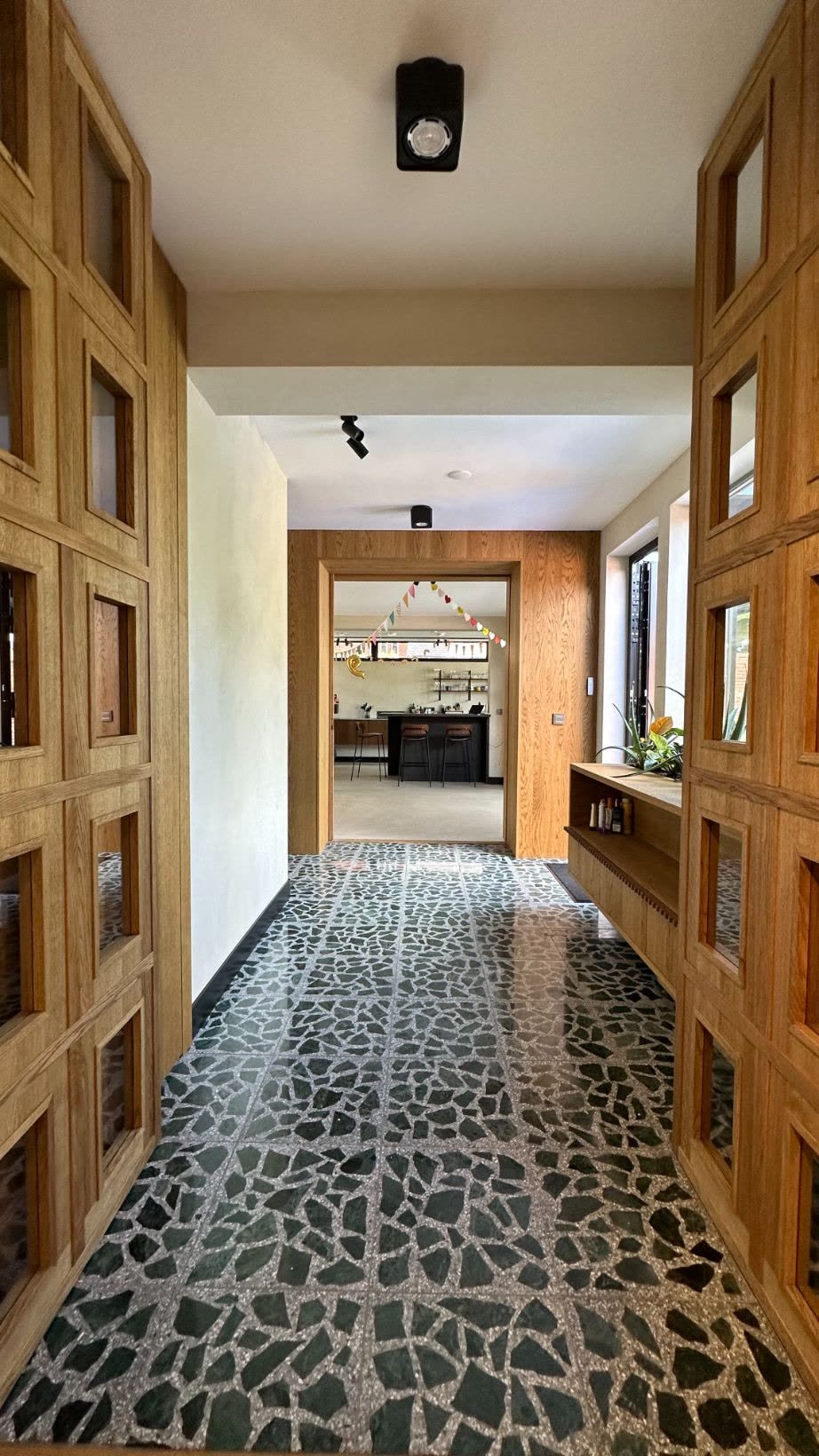 Long corridor with green marble terrazzo floor and a bespoke oak grid wardrobe wall