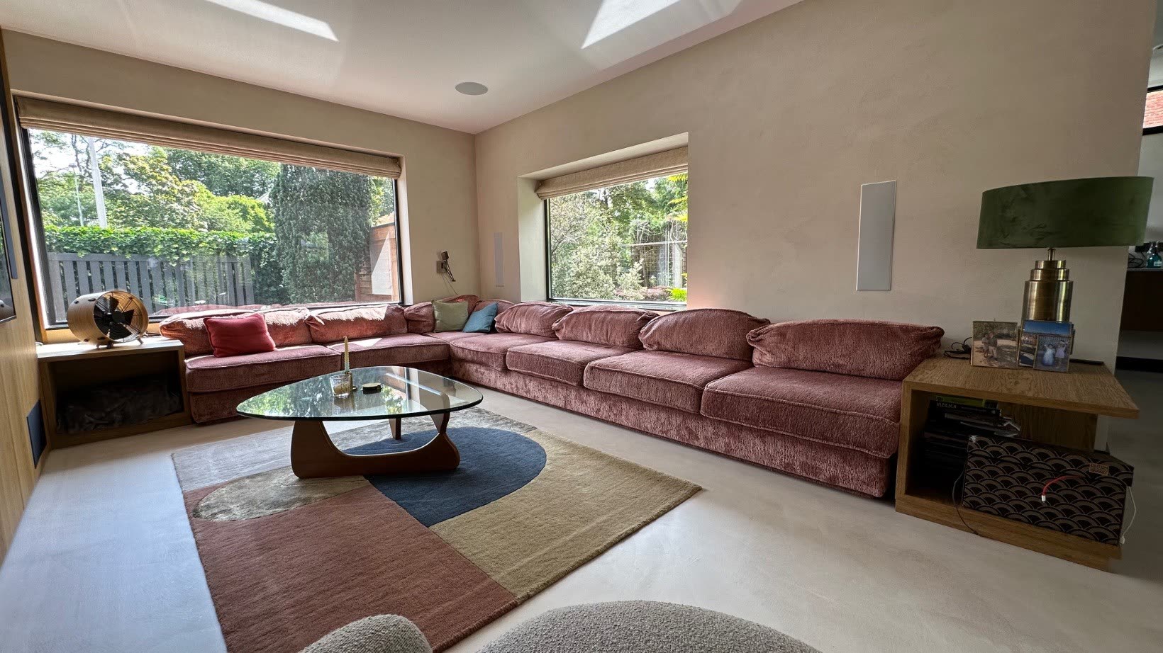 Living room with rose sofa and full-height windows onto the garden