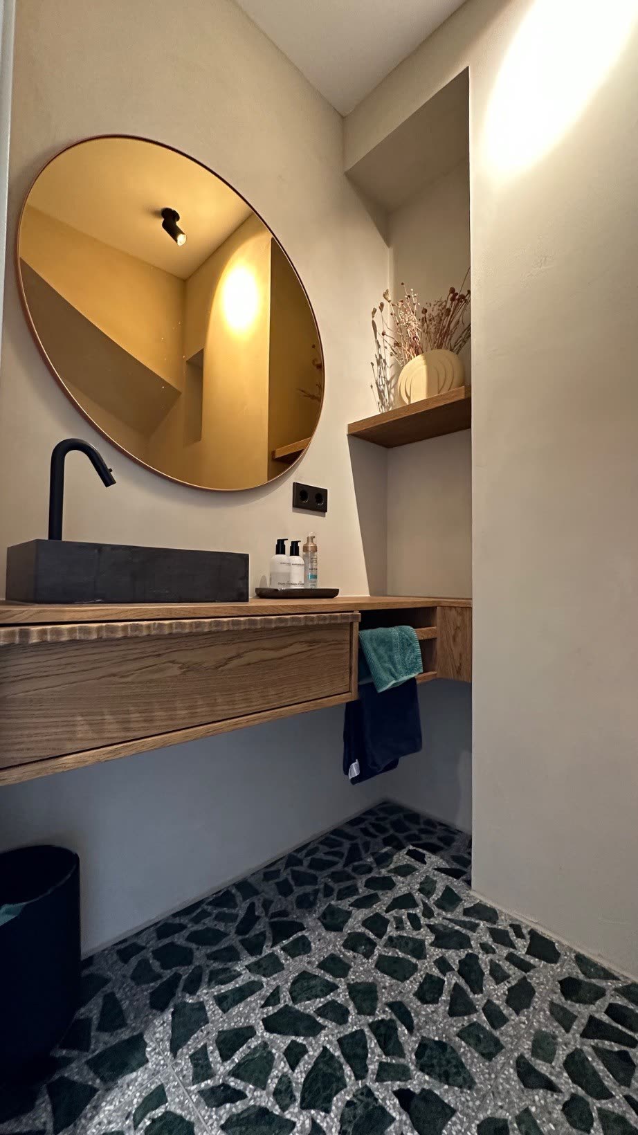 Guest cloakroom with oak vanity above a green terrazzo surface